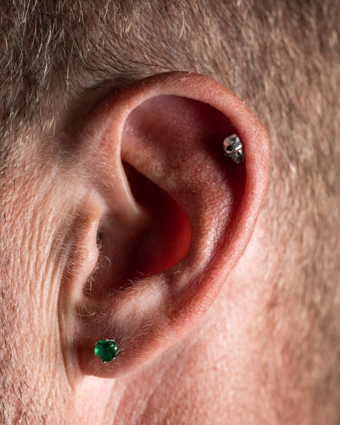Detailed view of a human ear featuring multiple piercings and an emerald stud. Perfect for jewelry and fashion themes.